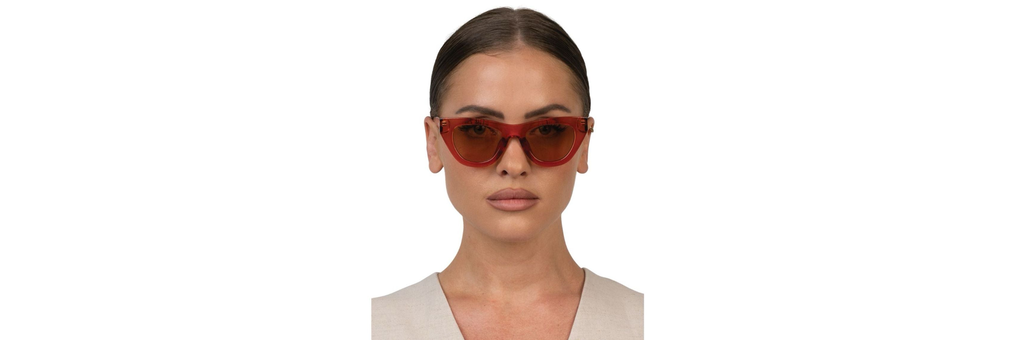 Close-up of oversized sunglasses on a sunny sidewalk showing tall lenses and wide temples that block light at the cheeks and temples.
