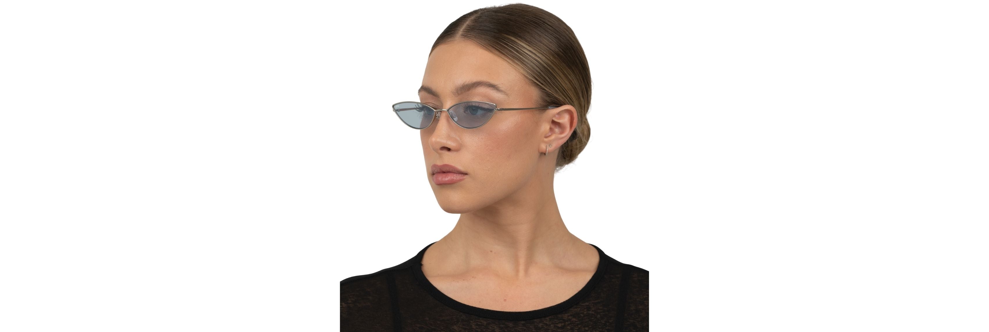 Two pairs of OTRA blue‑light glasses—one thin, minimalist cat‑eye and one bold geometric shape—sitting beside a laptop and ring light before a video call.