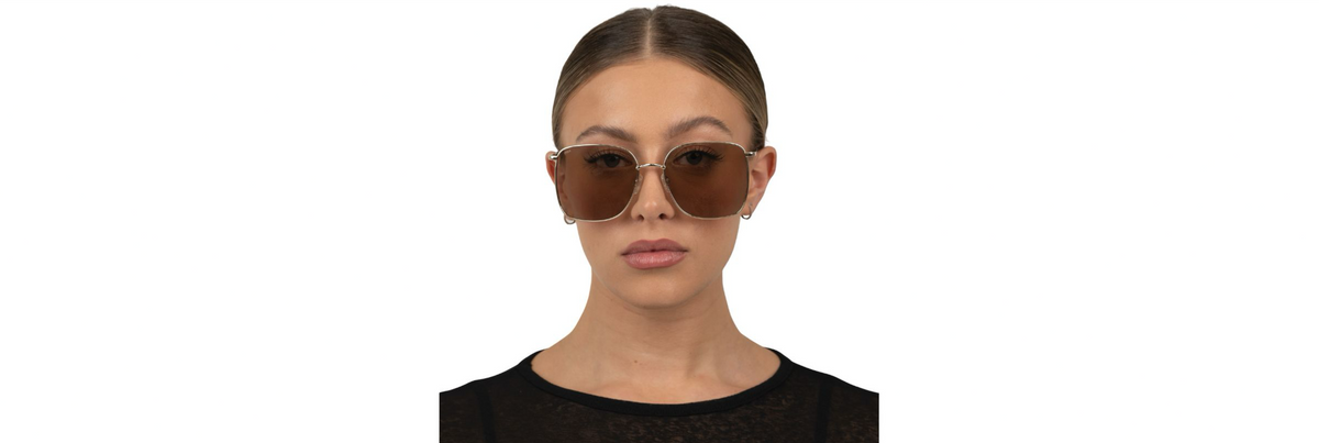 Side-by-side photo of a gold metal aviator and a tortoiseshell acetate frame resting on a sunlit poolside table, showing lens tints and nose pads in bright midday light.