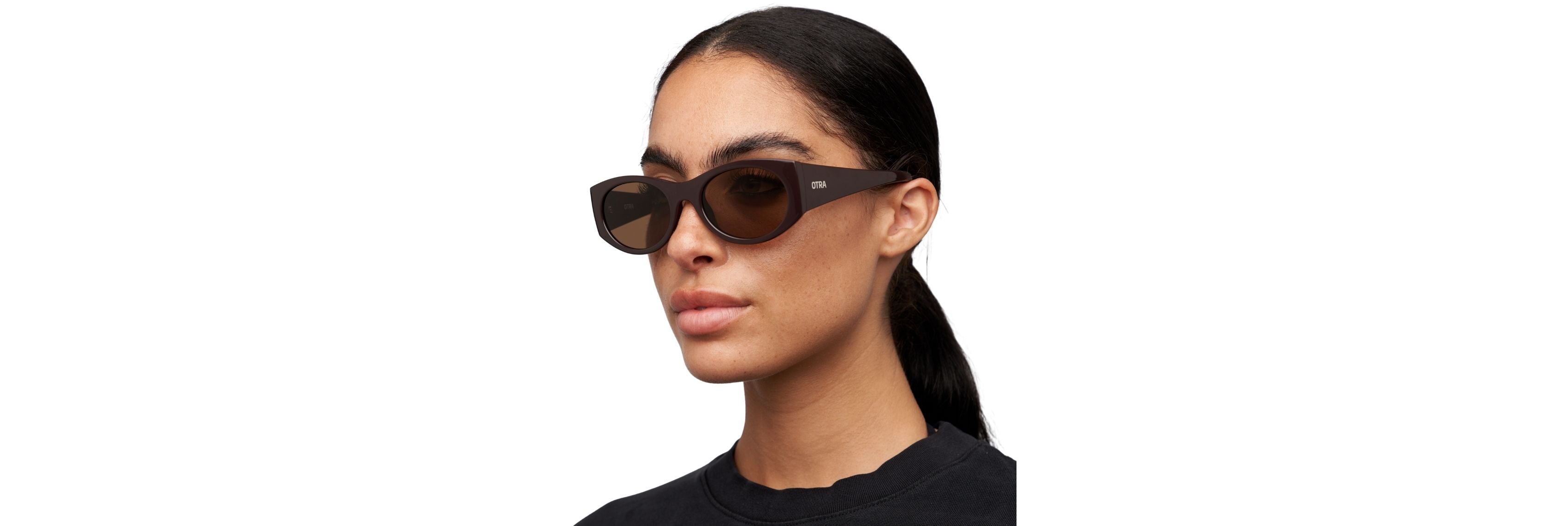 A woman in thin metal rectangle sunglasses and a neutral blazer stepping from desk to subway platform, showing a light, minimal silhouette.