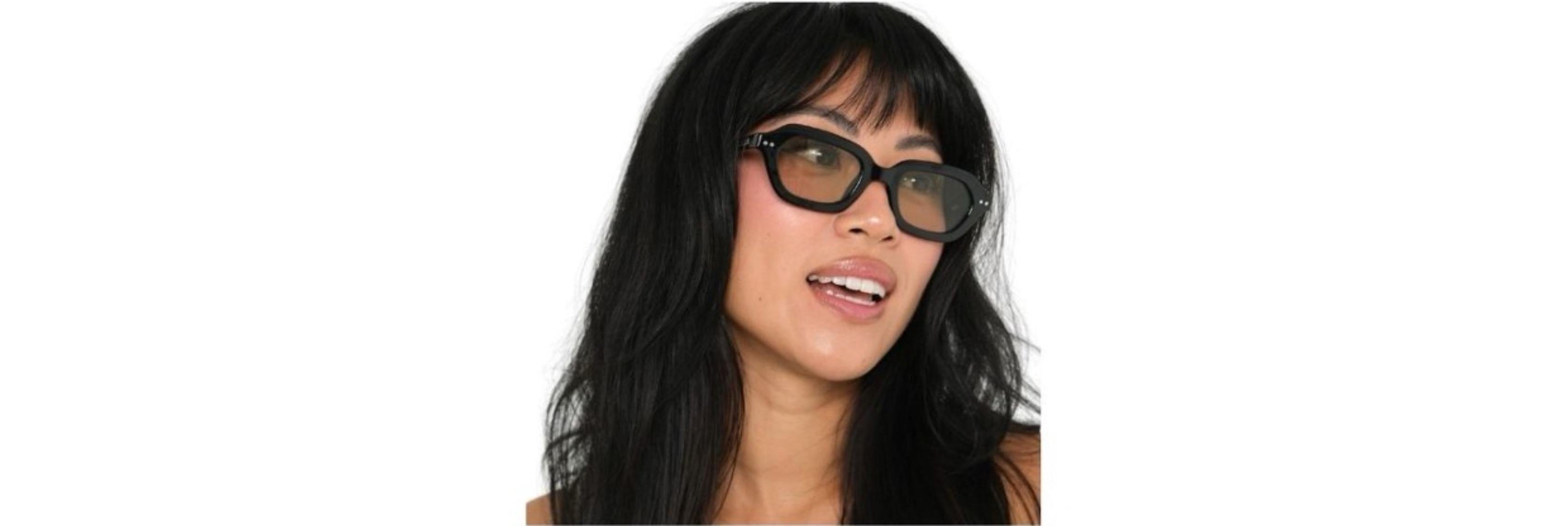 Close-up of a small-faced wearer in slim cat-eye sunglasses sitting above the cheek line with a medium-brown Category 3 tint on a sunny city street.