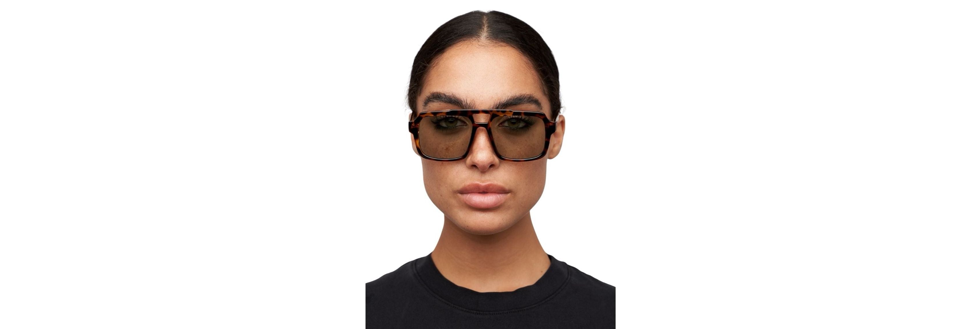 Open carry-on with clothing rolled and two sunglasses: one classic tortoiseshell pair and one darker sportier pair, plus a slim hard case.