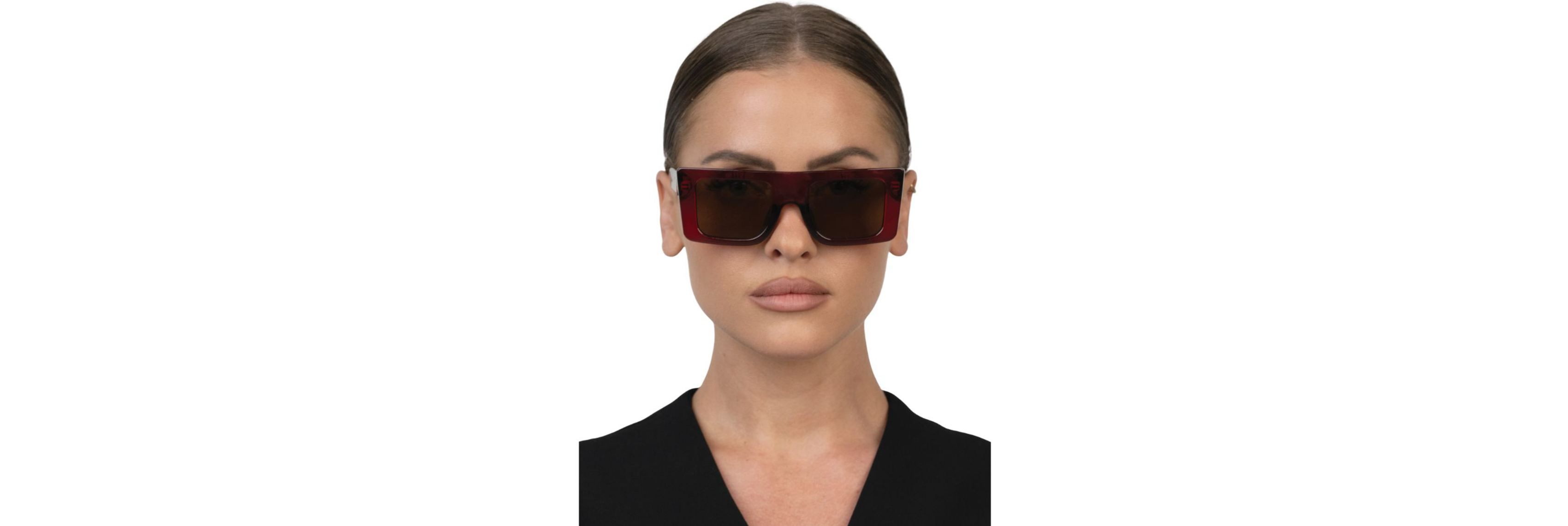 Close-up of OTRA sunglasses with brown gradient lenses softening reflections on a sunny city sidewalk.