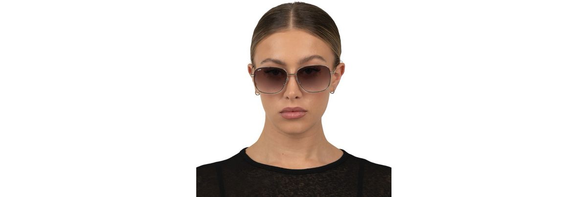 A transparent olive aviator with brown‑fade lenses next to a black frame with deep green lenses, photographed at golden hour with LED lights in the background.